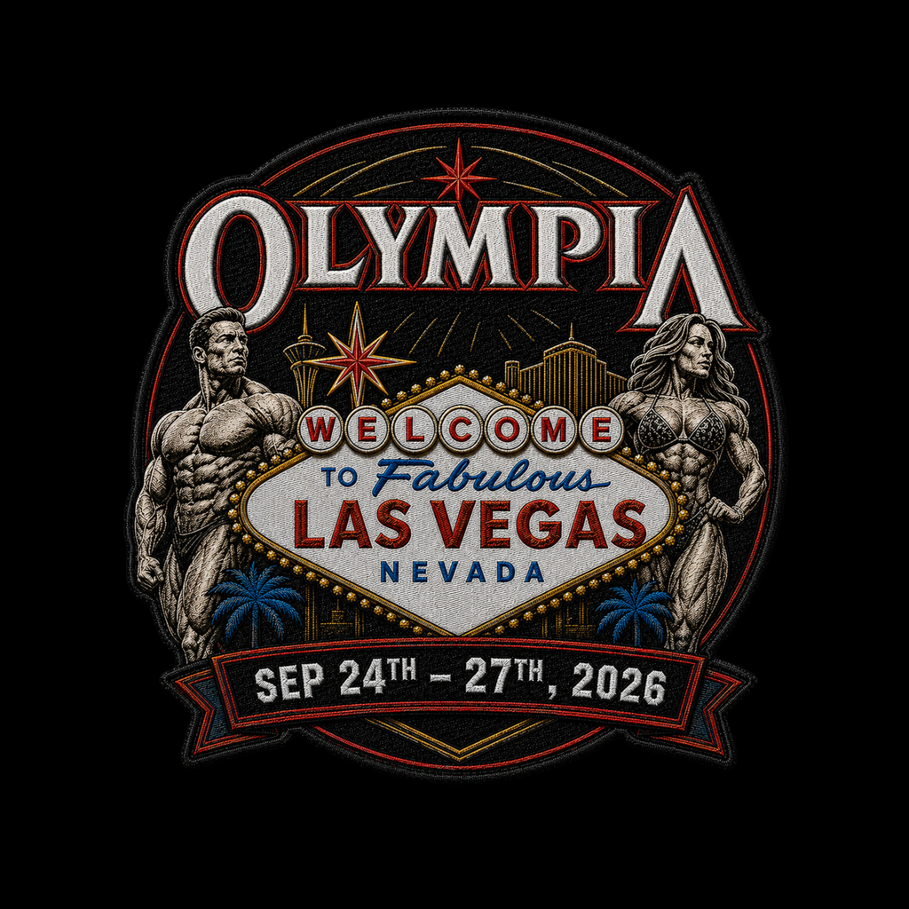 A circular embroidered patch design featuring the word 'OLYMPIA' at the top, a 'Welcome to Fabulous Las Vegas Nevada' sign in the center, two muscular female bodybuilders flanking the scene, and a red ribbon at the bottom reading 'SEP 24TH - 27TH, 2026'. The patch is shown on a solid black background.